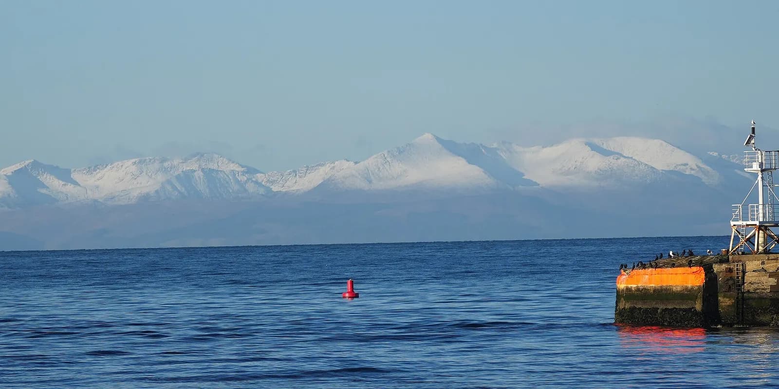 The snow-capped peaks of Arran across the Firth of Clyde, seen past the end of Ayr harbour pier